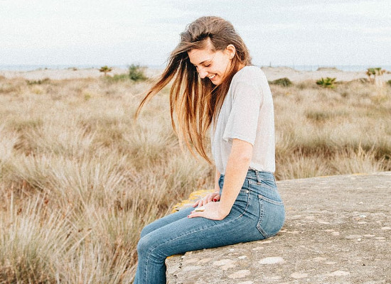 Girl sitting on a stone with a wide horizon in the background