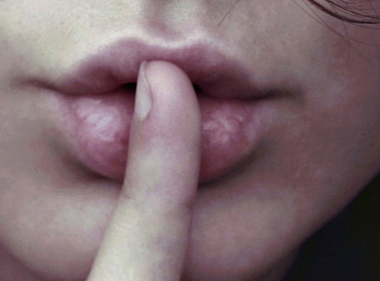 Quiet sign formed with finger and lips